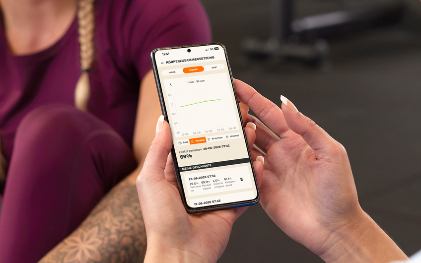 Mitglied verfolgt die Entwicklung der Muskelmasse in der Basic-Fit App w&auml;hrend des Trainings.