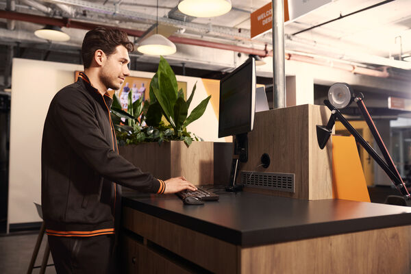 Ein Mitarbeiter arbeitet hinter dem Empfangstresen eines Basic-Fit Clubs.