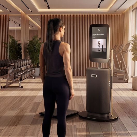 Frau steht vor einer EGYM-Onboarding-Station, w&auml;hrend der Bildschirm Einrichtungsanweisungen f&uuml;r ihren Trainingsplan zeigt.