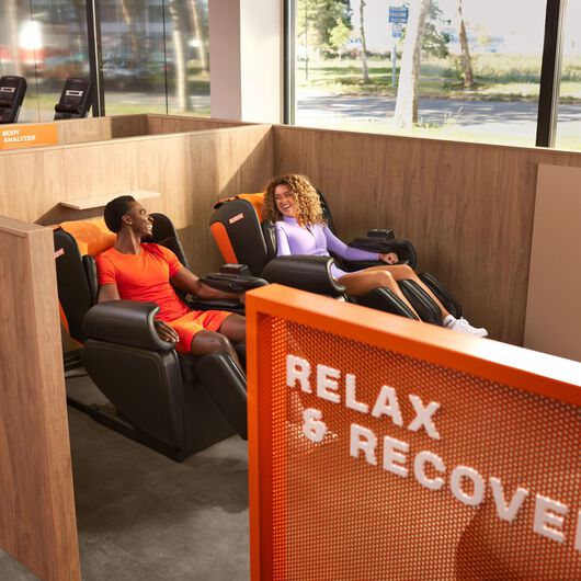 Two people relaxing in the Relax & Recover area at a Basic-Fit club.