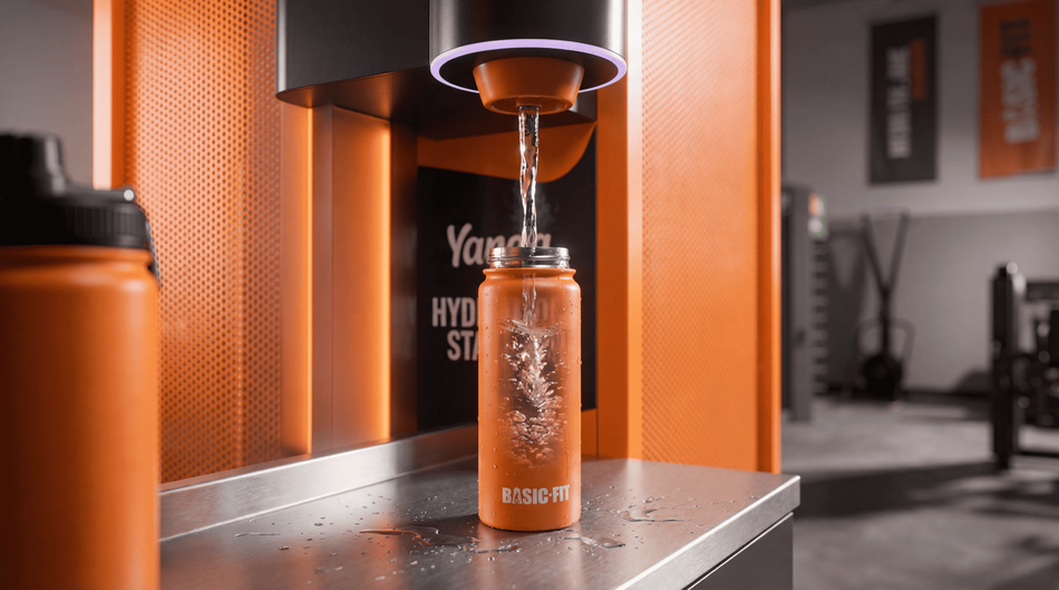 Orange Basic-Fit bottle being filled at a Yanga Sports Water station.