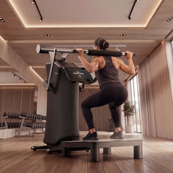 Frau f&uuml;hrt eine gef&uuml;hrte Kniebeuge an einem EGYM-Kraftger&auml;t mit &Uuml;bungsfeedback auf dem Bildschirm aus.