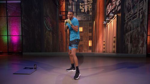 Hombre en postura de boxeo en el estudio, listo para un entrenamiento cardiovascular intenso.