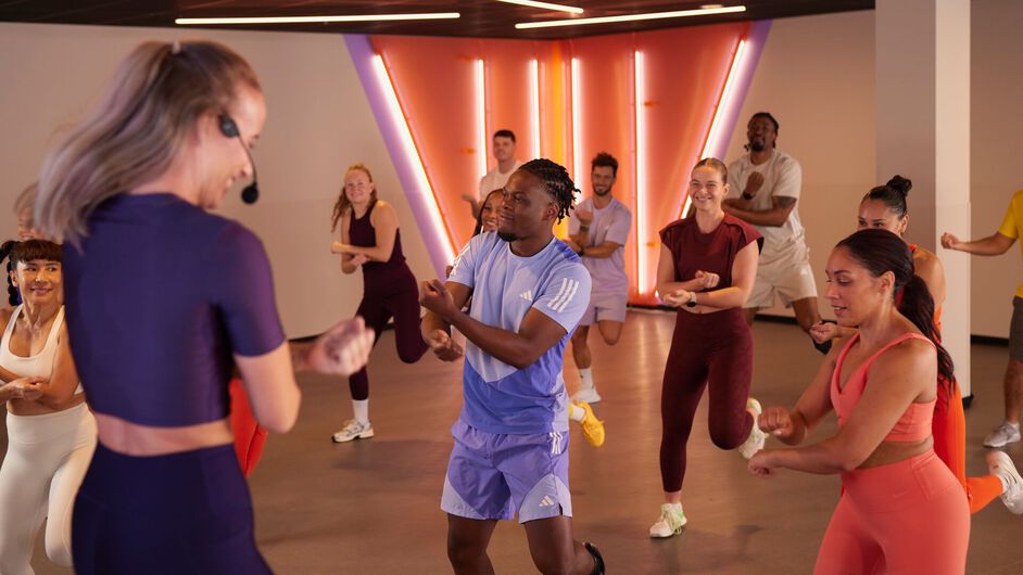 Een groep doet mee aan een Zumba-les en voert samen danspassen uit terwijl ze de instructeur volgen in de fitnessstudio.