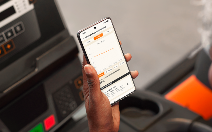 Membre consultant l'&eacute;volution de sa masse musculaire dans l'application Basic-Fit pendant son entra&icirc;nement.