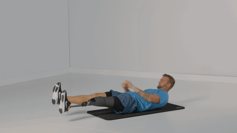 Hombre tumbado sobre una esterilla realizando un ejercicio abdominal dinámico con las piernas elevadas