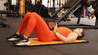 Person performing a hip bridge while holding a dumbbell across the hips.