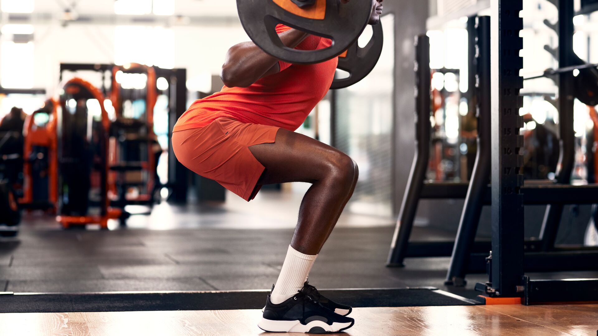 Homme effectuant des squats avec une barre dans une salle de sport pour renforcer les fessiers