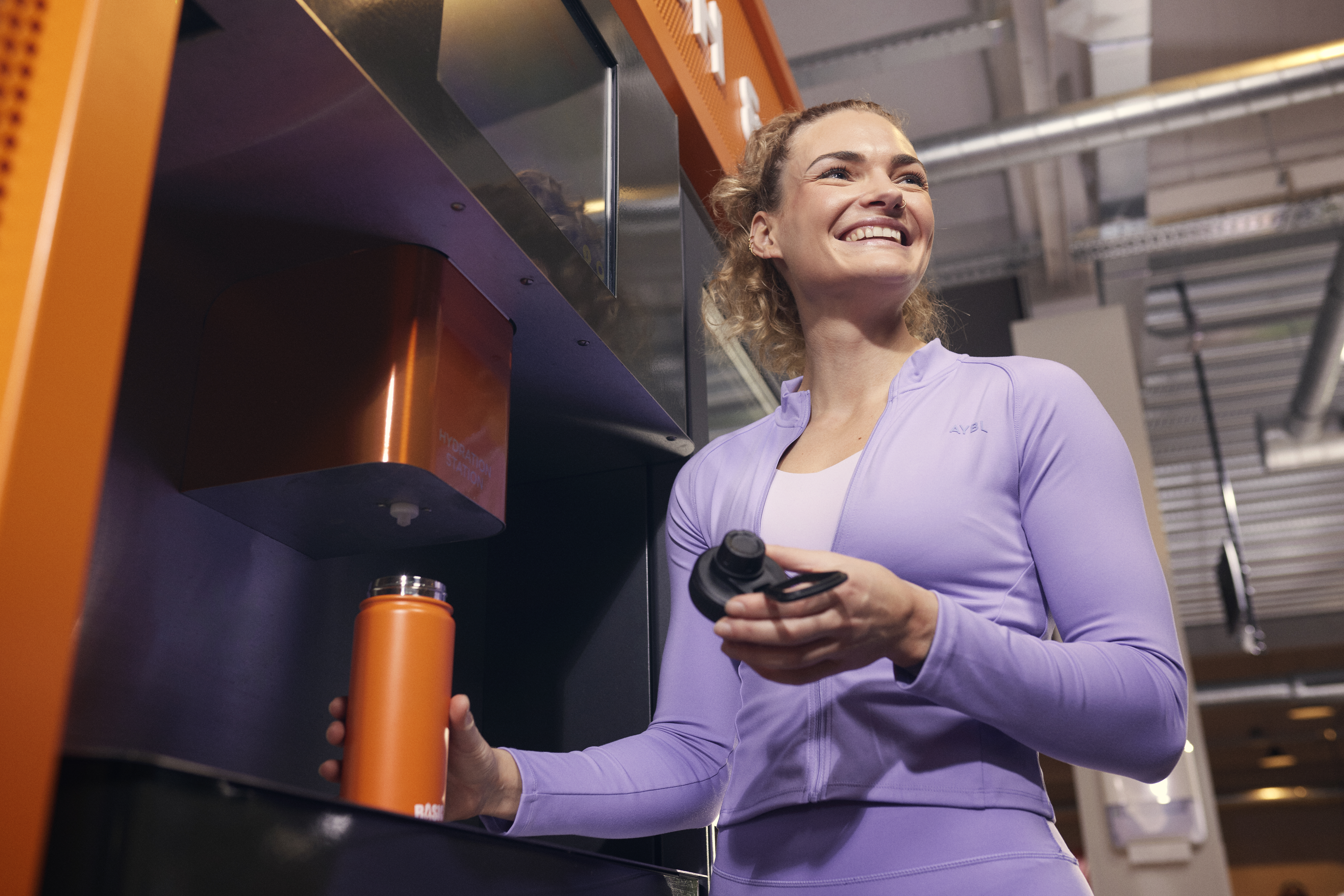 Una persona rellena su botella con YANGA durante un entrenamiento en Basic-Fit