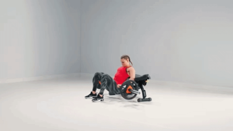 Woman setting up for a hip thrust on a bench, feet flat on the floor and shoulders supported, preparing for the movement