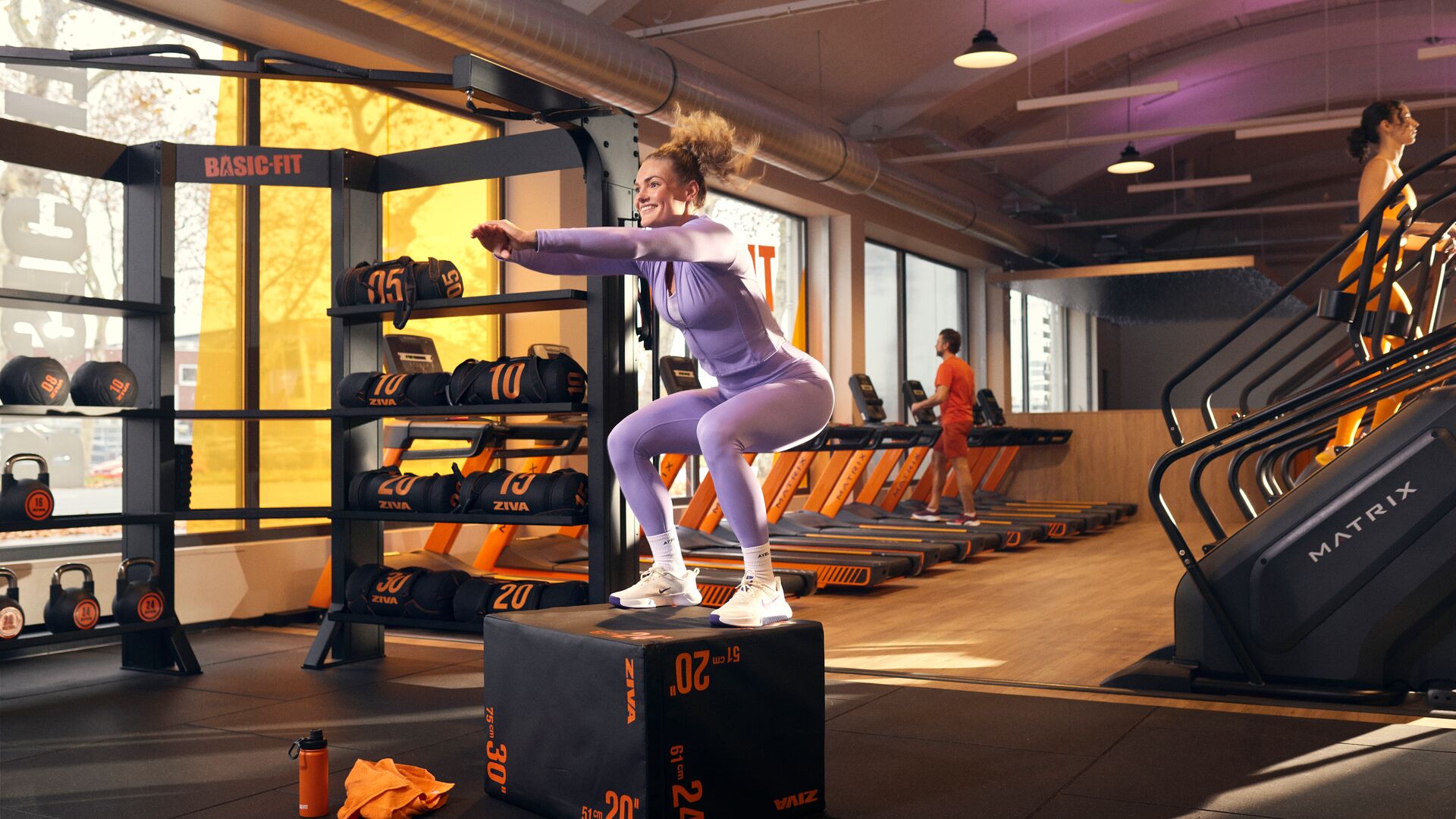 Mujer realizando un box jump en la zona de entrenamiento funcional de un club Basic-Fit