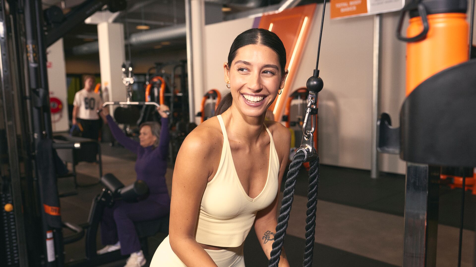 Woman in light sportswear using a cable machine for a tricep exercise in the gym.