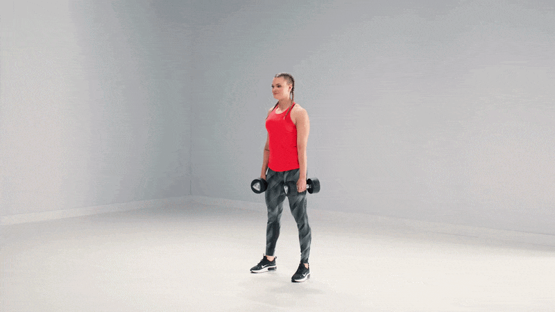 Mujer hace una sentadilla con mancuernas en un entorno de entrenamiento en estudio